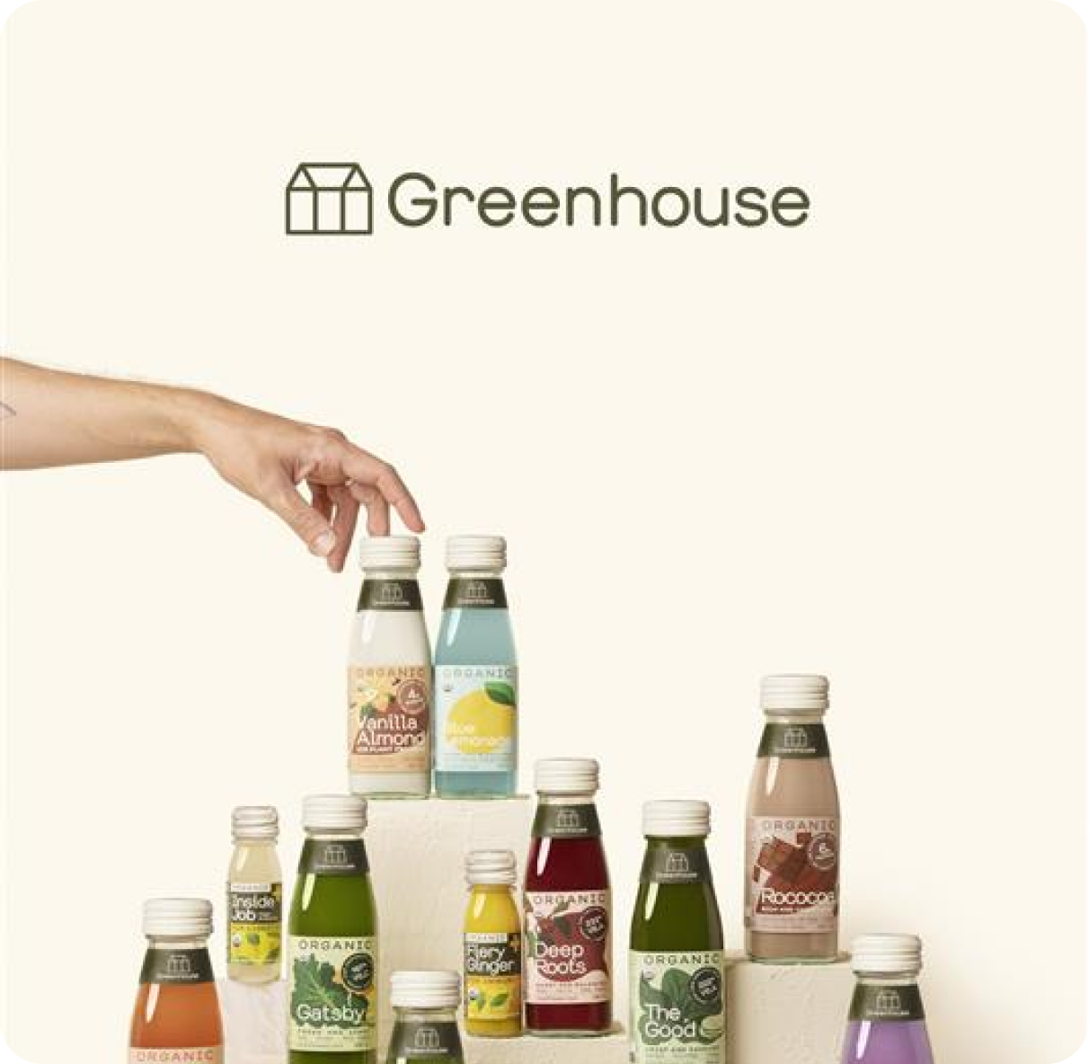 Hand reaching for a juice bottle on the top of a stack of bottles 